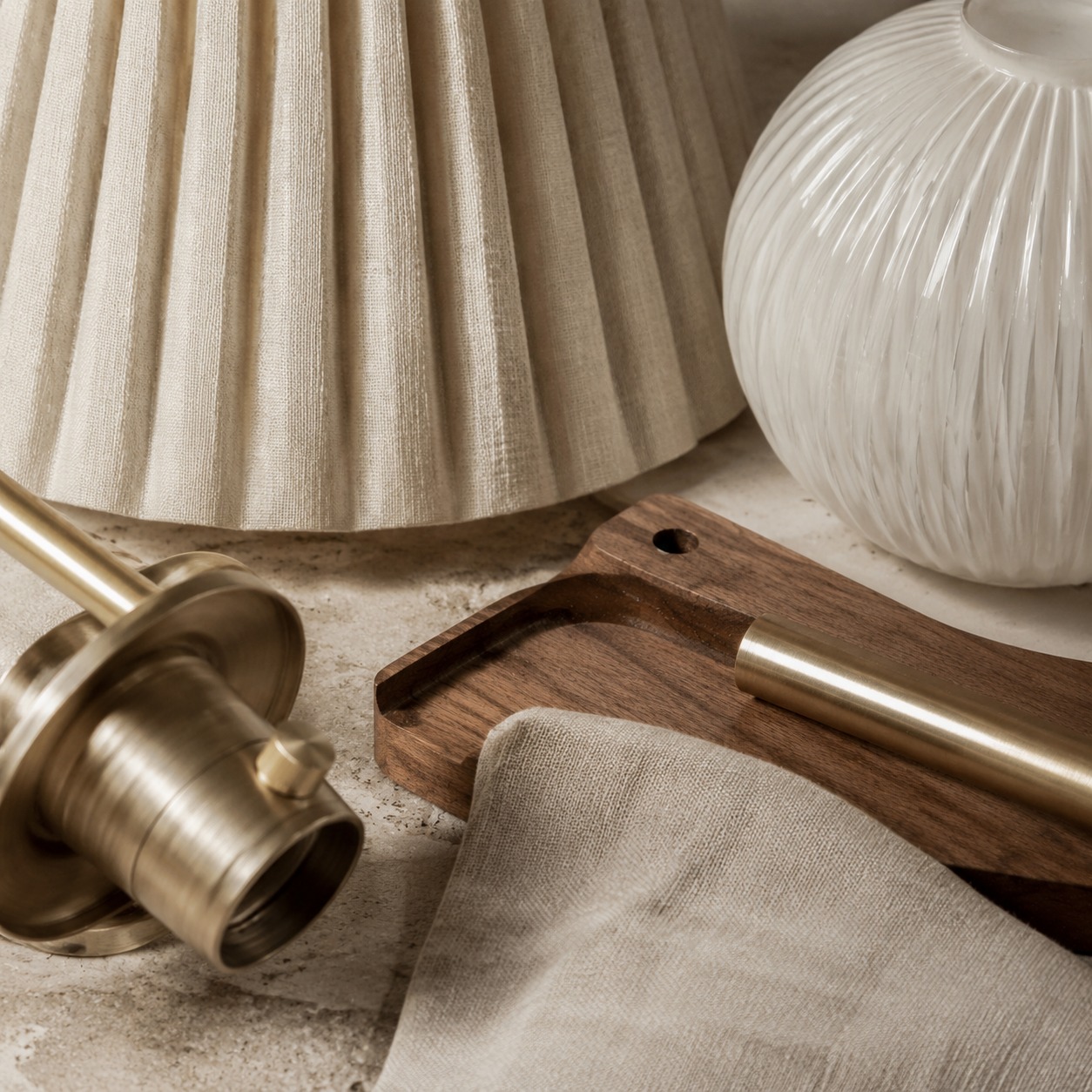 Close-up of linen, textured glass, warm wood and brushed metal