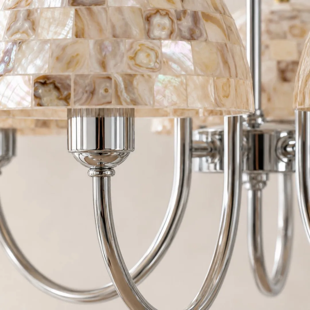 Close view of beige shell mosaic shades and polished metal chandelier arms