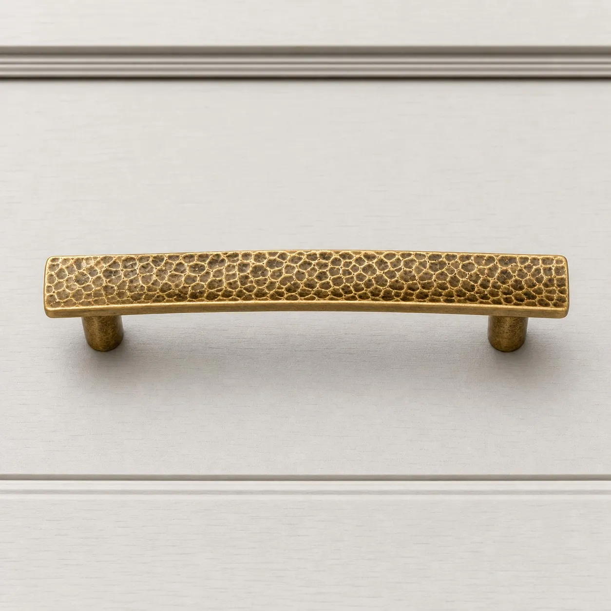 Hammered brass cabinet pull on white cabinet drawer